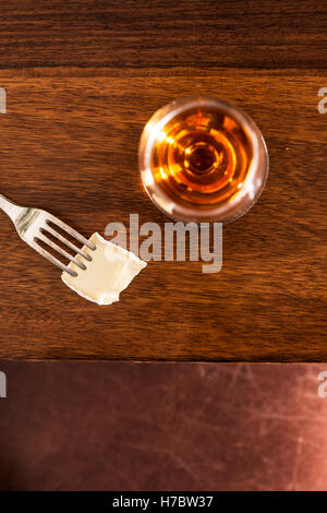 Sherry in a glass and a piece of brie cheese on a fork. Snack or appetizer. Stock Photo