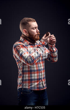 Elegant bearded man holding smoking pipe Stock Photo