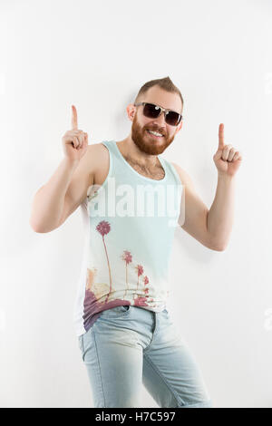 Portrait of young smiling bearded man in sunglasses showing thumbs up Stock Photo