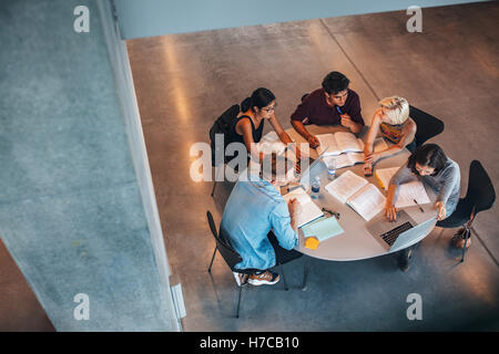 Multiethnic group of young people studying together at a table. Young students in cooperation with their school assignment. Stock Photo