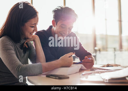 Happy young male and female students reading a book together in class. university students studying together in library. Stock Photo