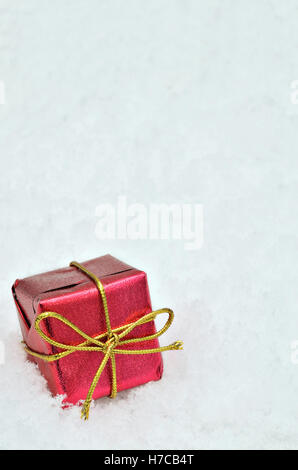 single small red metallic bright parcel on snow background, close up, space for text,  vertical Stock Photo