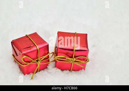 two small red metallic bright parcels on snow background, close up, space for text, horizontal Stock Photo