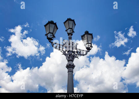 Old, historical, ornamental street lamp from bottom view in Berlin. Blue, cloudy sky makes the background. Symmetrical compositi Stock Photo