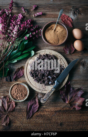 Chopped chocolate, coconut sugar, eggs and cacao powder on wooden table Stock Photo