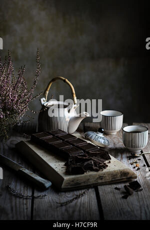 Tea time: teapot, cups of tea and dark chocolate on wooden table Stock Photo