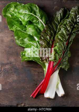 Variety of fresh chard mangold salad leaves over old dark wooden background. Top view with space for text. Healthy eating theme. Stock Photo