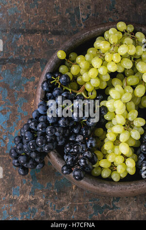 Bunch of ripe wet red and white grapes in clay tray over old dark wooden background. Top view with space for text Stock Photo