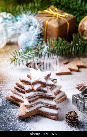 Stack of homemade Christmas shortbread star shape sugar cookies different size with sugar powder on old wooden surface with Chri Stock Photo