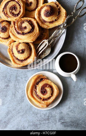 Puff pastry cinnamon rolls on tray with a cup of coffee.Top view Stock Photo