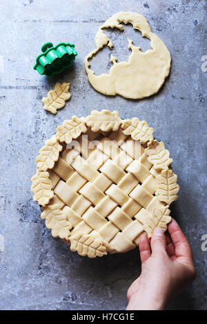 Female hand decorating a pie with leaves .Top view. Stock Photo