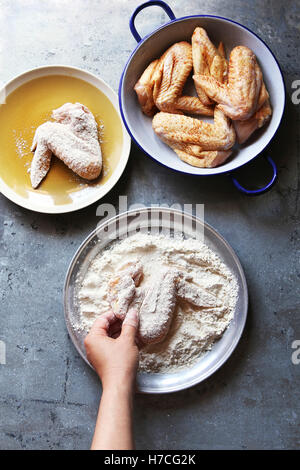 Female hand coating raw chicken wings with flour before frying.Top view Stock Photo