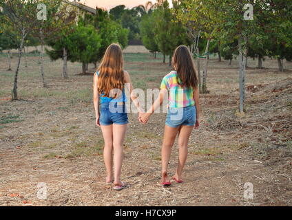 Best Friends Forever - two 12 year old teenage girls  holding hands at sunset Stock Photo