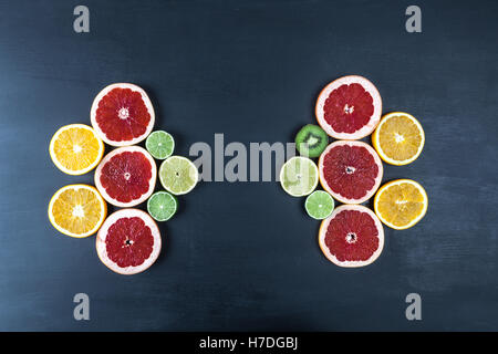 Creative arrangement of slices of citrus fruits on black painted surface. Top view with copy space. Stock Photo