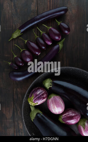 Classic, baby, Japanese, and purple striped eggplants arranged on wooden table. Vertical image, top view. Stock Photo