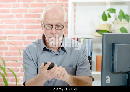 Middle Aged Businessman Sitting at Desk, with  phone Stock Photo