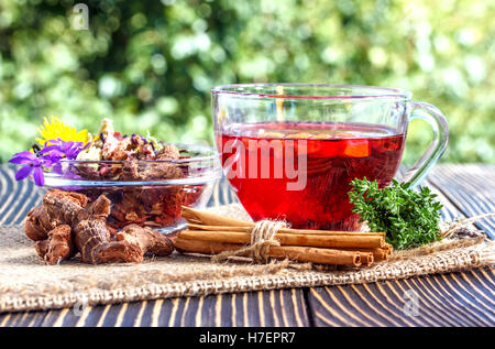 Cup of herbal tea with  various herbs and dried fruit on a wooden table outdoors Stock Photo