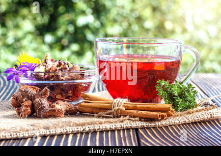 Cup of herbal tea with  various herbs and dried fruit on a wooden table outdoors Stock Photo
