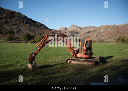 Orange mini digger in the Langdale Valley, Lake District, Cumbria, UK. Stock Photo