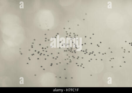 Little silver mirror stars scattered on paper background and fuzzy balls glitter in sepia tone. Stock Photo
