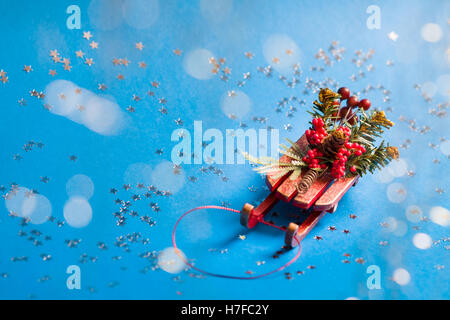 Christmas card with shine silver star and decorative sled standing on blue background in blurred glow balls. Stock Photo