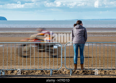 A lone spectator looks on as a motorcyclist  races by at Weston beach race, Somerset UK. Stock Photo