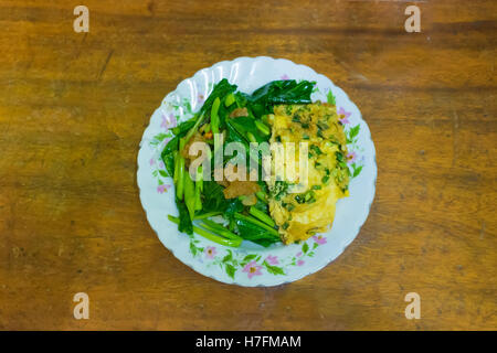 Crispy Pork with Kale ,Stir fried kale with crispy pork, omelet and rice on wood table, Thai food Stock Photo