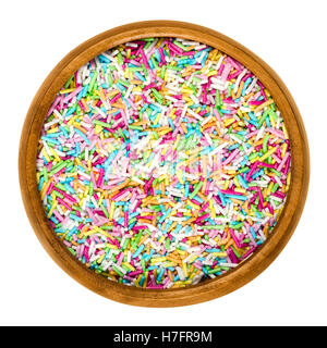 Colorful sugar sprinkles for food decorations in wooden bowl on white background. Multi colored bakery decoration ingredient. Stock Photo