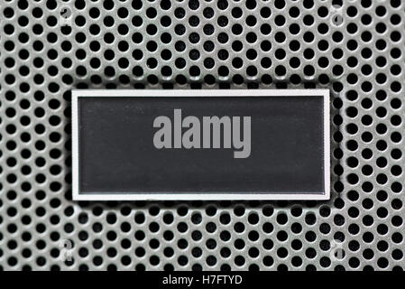Metal plate label on metal steel grid with repetitive rows of punched circular holes, background and texture, Metal Grid for ind Stock Photo