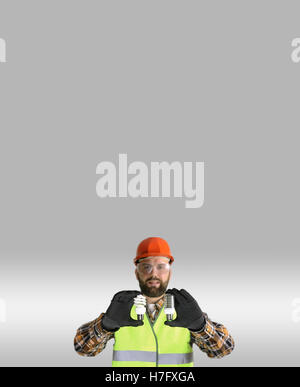 Worker in a helmet and protective clothing with a light bulb in Stock Photo
