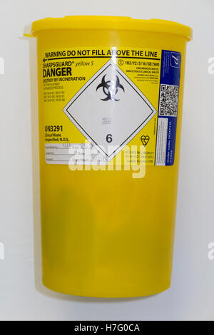 Hospital type sharp waste bin on the wall of a clinic, for the safe disposal of medical sharps paraphernalia. Stock Photo