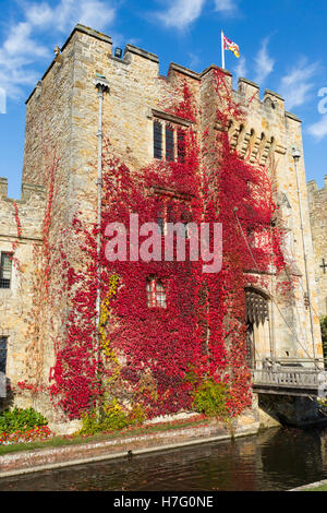 Hever Castle & moat, former home of Anne Boleyn, clad with red autumnal virginia creeper & blue sky / sunny skies / sun. Kent UK Stock Photo