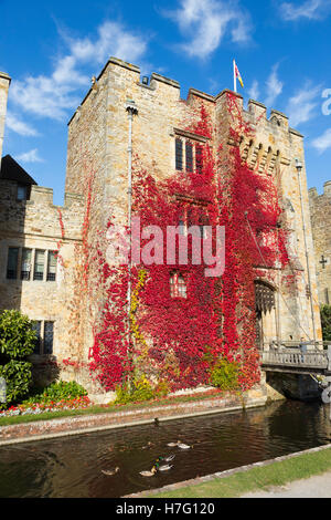 Hever Castle & moat, former home of Anne Boleyn, clad with red autumnal virginia creeper & blue sky / sunny skies / sun. Kent UK Stock Photo
