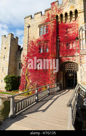 Hever Castle clad with red autumnal virginia creeper: Blue sky / sunny skies / sun & drawbridge / draw bridge over moat. Kent UK Stock Photo