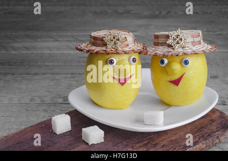 Lemons with sugar on a white plate and grey wooden background Stock Photo