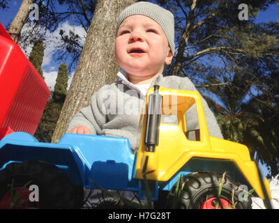 Baby boy playing with dump truck in the park a sunny winter morning Stock Photo