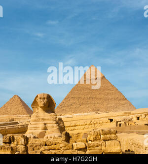 Front facing Sphinx and the large Egyptian Pyramids of Khafre, Menkaure slightly offset in front of blue sky in Cairo, Egypt