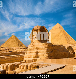 Egyptian Great Sphinx full body portrait with head, feet with all pyramids of Menkaure, Khafre, Khufu  in background on a clear, Stock Photo