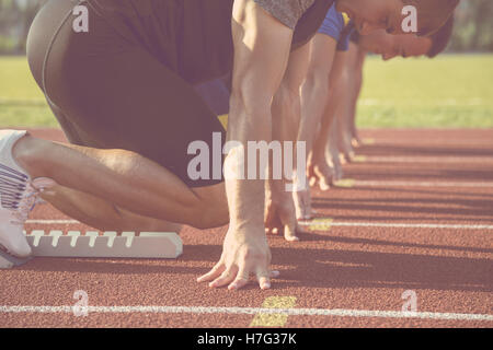 Male athletes at starting line on sunny day. Stock Photo