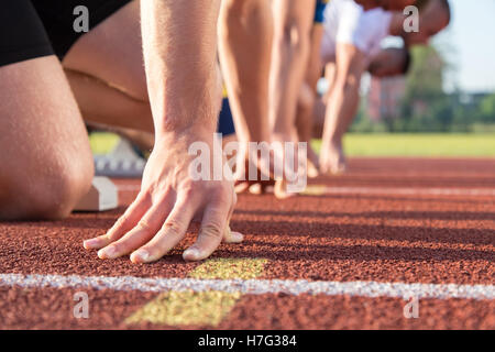 Male athletes at starting line on sunny day. Stock Photo
