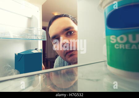 hungry man with funny face opens the fridge Stock Photo