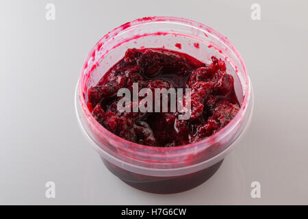Black currant jam in the round plastic container on white background Stock Photo