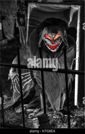 Zombie escapes a box. Red eyes. Behind fence. Halloween decorations. Halloween yard display. Stock Photo