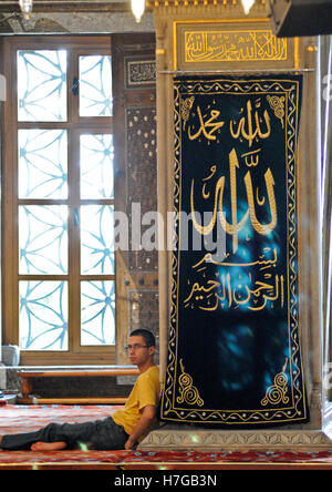 Muslim man resting inside the Blue Mosque, Istanbul, Turkey Stock Photo