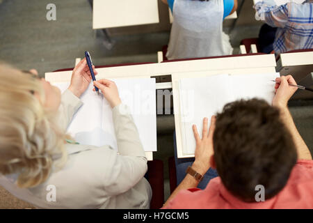 students with notebooks at exam or lecture Stock Photo