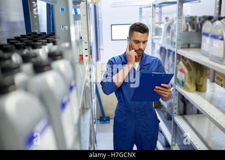 auto mechanic calling on smartphone at car shop Stock Photo