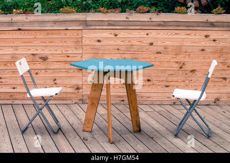 Two empty white modern chairs with blue table on the wooden floor of the theatre. Nobody is sitting. Stock Photo