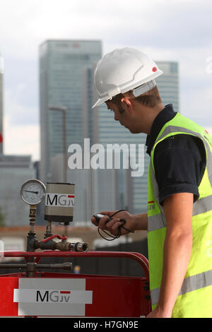 waste water worker checking valves with London skyline in background Stock Photo