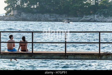 Two young people sitting on the pier Stock Photo