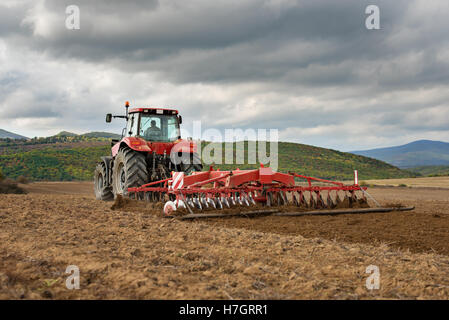 Farmer in tractor preparing land with seedbed cultivator Stock Photo